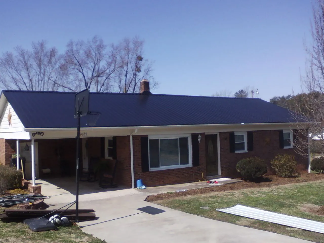 Finished dark blue metal roof on a brick ranch with a carport in Elkland