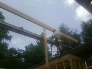Carpenter setting a ridge beam over a new addition frame — Ice Dam Removal by Roofing Brothers in Elkland
