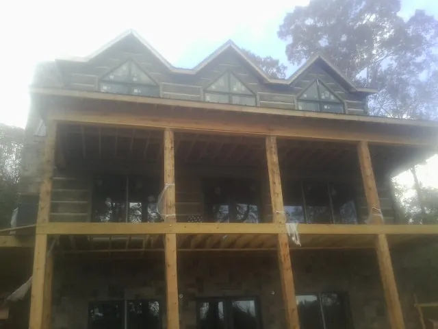 Dormers and porch framing on a large log home under construction — Roof Coating work by our crew in Elkland