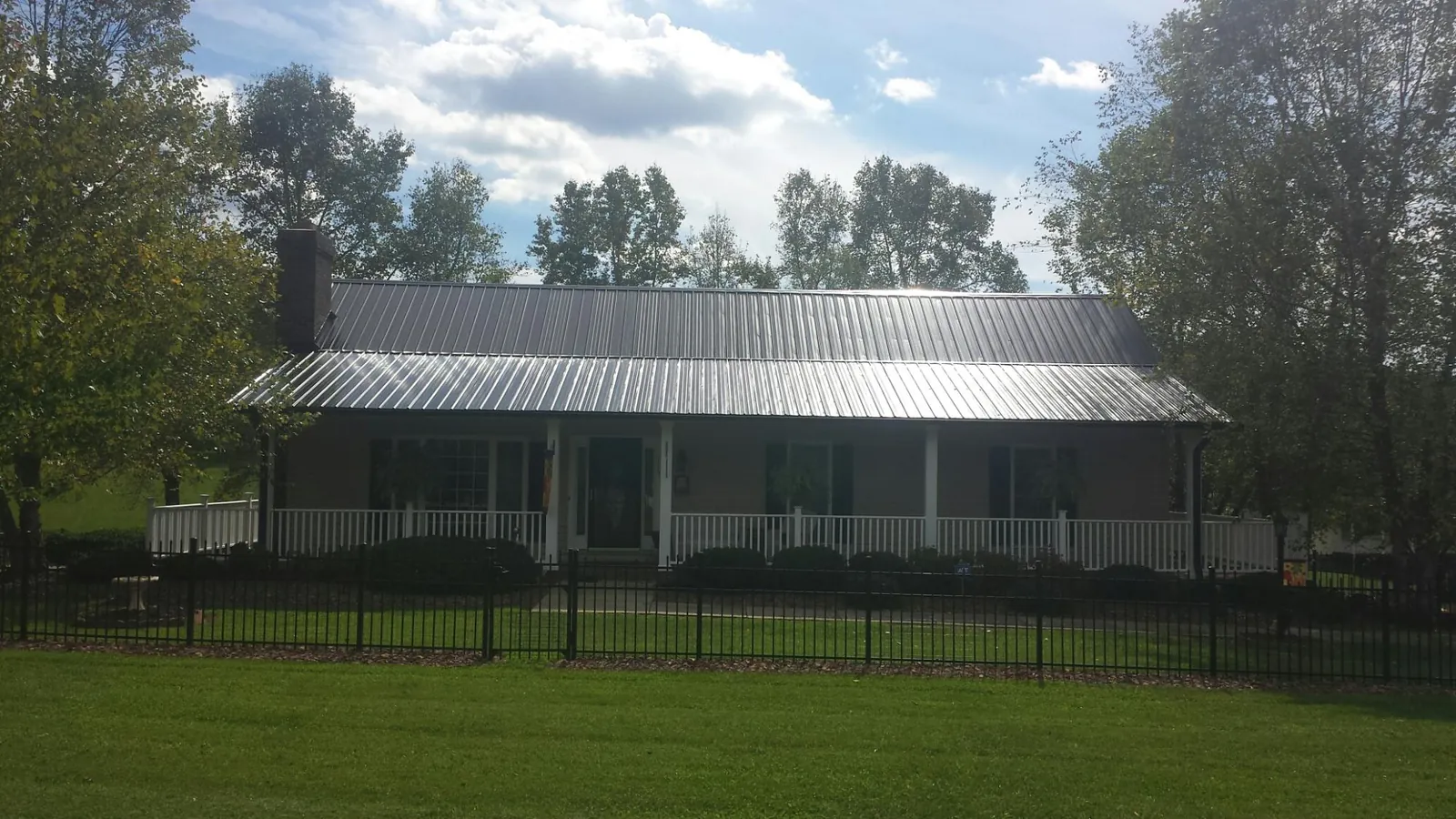 Gray metal roof on a brick ranch with a full width front porch — Gutter Guard Installation work by our crew in Elkland
