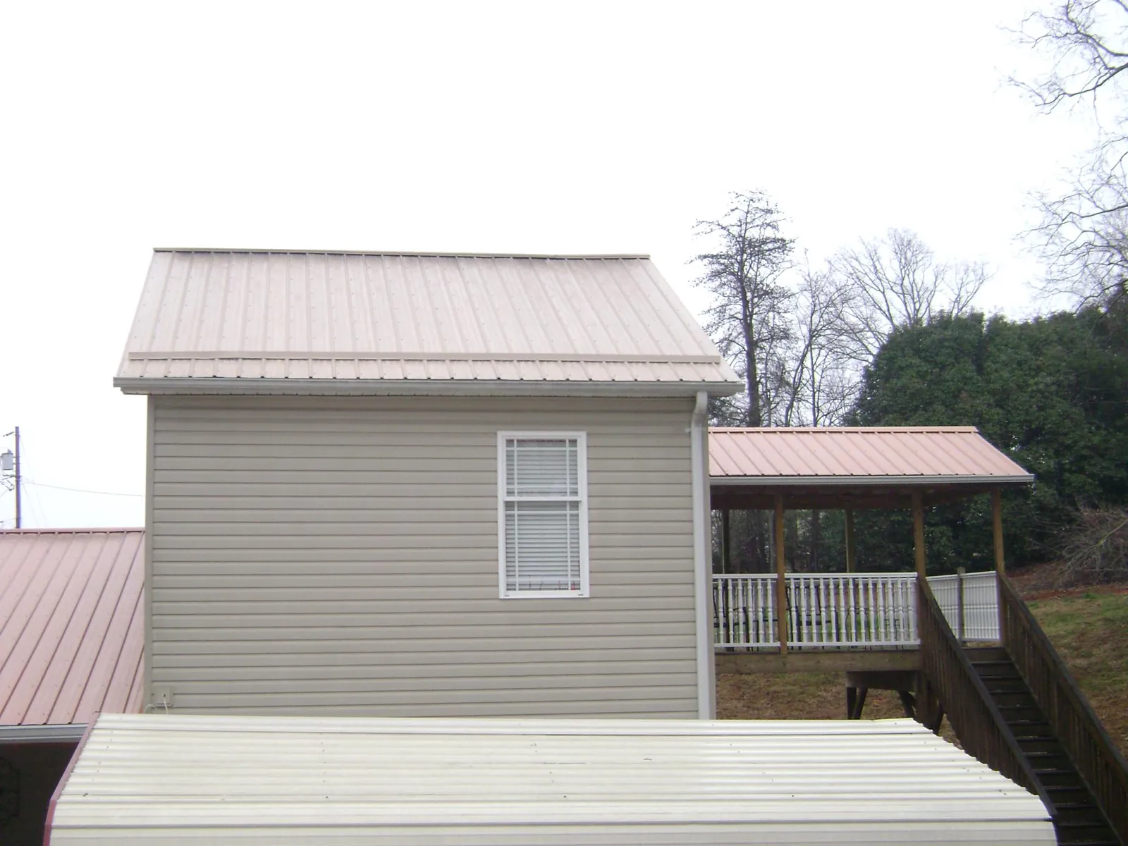 Tan metal roofs on a two story addition and attached porch, from a Roof Replacement job in Elkland