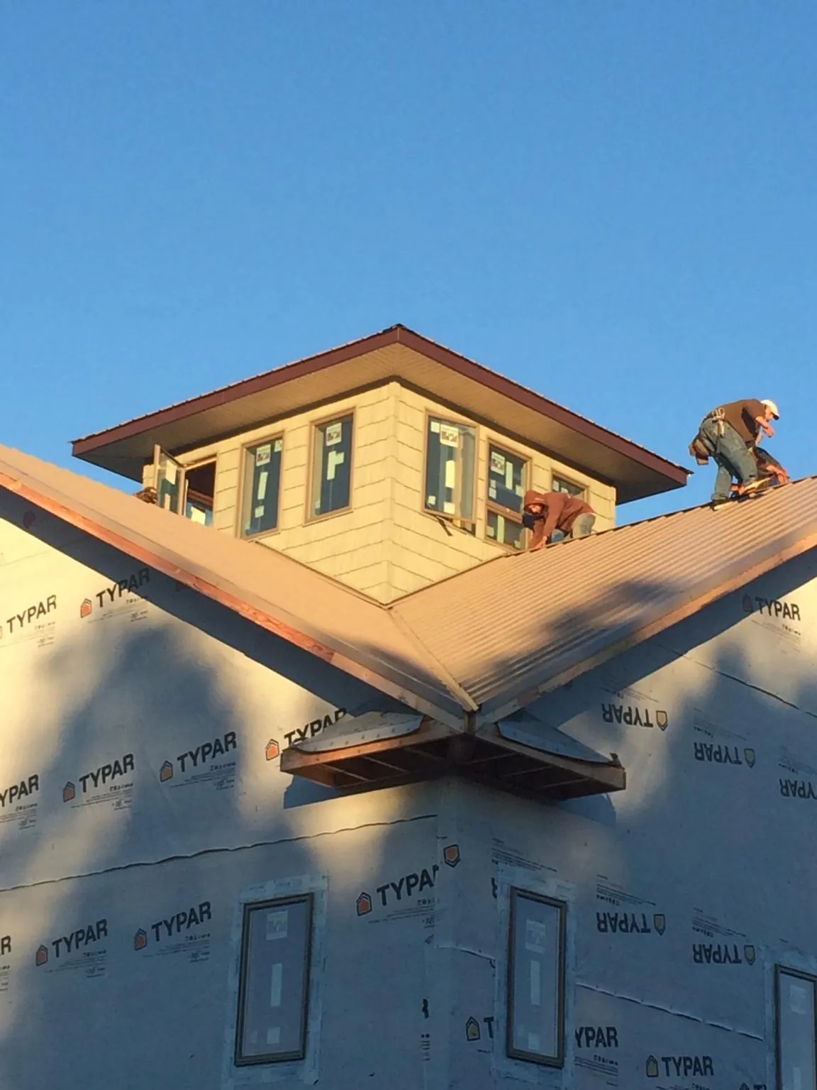 Roofers working around a rooftop cupola on a new metal roof at sunset — Roof Waterproofing in Elkland by Roofing Brothers